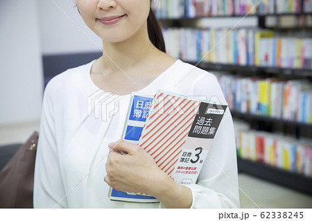 資格の勉強をする女性（参考書の表紙はピクスタ撮影のために作成されたダミーです） 62338245