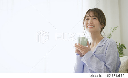 パジャマ姿でマグカップを持つ女性 62338652