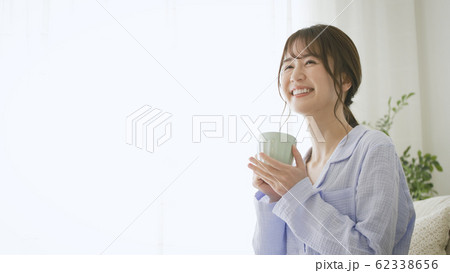パジャマ姿でマグカップを持つ女性 62338656
