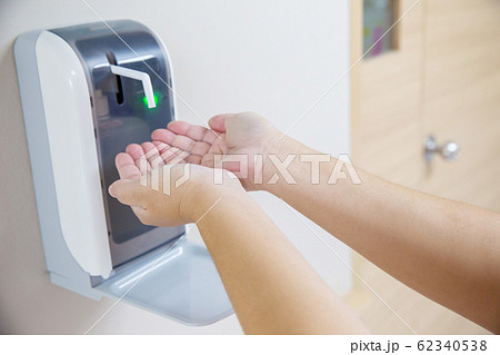 Hands under the automatic alcohol dispenser. Infection and hospitably concept. Hands under the automatic alcohol dispenser. Infection and hospitably concept. 62340538