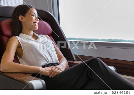 Happy commuter enjoying train travel to go to work in the morning. Asian woman enjoying view passing by relaxing in comfortable business class seat 62344105