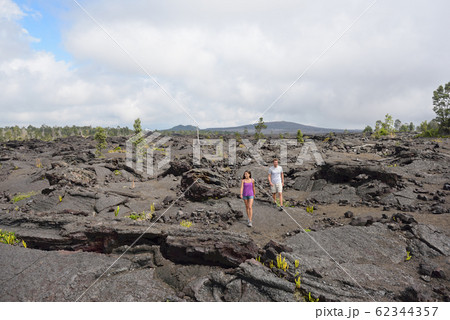 Hawaii destination travelers couple hiking in volcanic rocks on Kilauea volcano in Big island of Hawaii Hawaii destination travelers couple hiking in volcanic rocks on Kilauea volcano in Big island of Hawaii 62344357