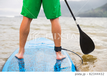 Paddleboard man paddling on SUP stand up paddle board on lake. Closeup of feet and legs Paddleboard man paddling on SUP stand up paddle board on lake. Closeup of feet and legs 62344432