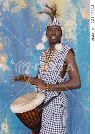 African artist in traditional clothes playing djembe drum 62347612