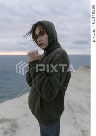 Rear tracking shot - a young woman jogging and boxing. Training in nature - a girl practices box while running 62348299