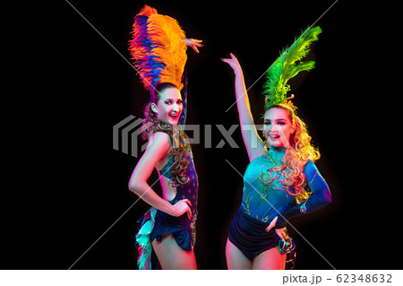 Beautiful young women in carnival and masquerade costume in colorful neon lights on black background 62348632