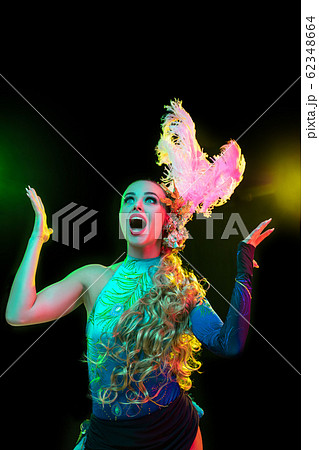 Beautiful young woman in carnival and masquerade costume in colorful neon lights on black background Beautiful young woman in carnival and masquerade costume in colorful neon lights on black background 62348664