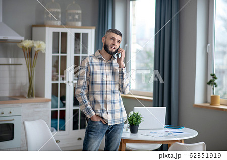 Young serious man talking on a smartphone at home. Young serious man talking on a smartphone at home. 62351919