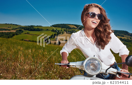 Young beautiful woman sitting on a italian scooter Young beautiful woman sitting on a italian scooter 62354411