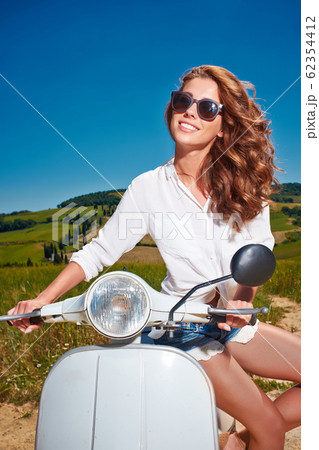 Young beautiful woman sitting on a italian scooter 62354412