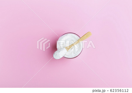 Collagen in a glass with a wooden spoon on a pink background 62356112
