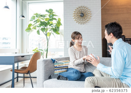 部屋でプレゼントを渡す若い男女のカップル 部屋でプレゼントを渡す若い男女のカップル 62356375