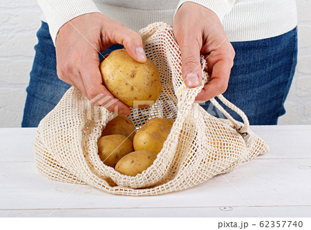 Woman put fresh potatoes in a textile bag Woman put fresh potatoes in a textile bag 62357740