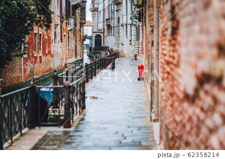 Venice, Italy. The small streets and narrow channel with colored brick houses on the shore of old city Venice, Italy. The small streets and narrow channel with colored brick houses on the shore of old city 62358214