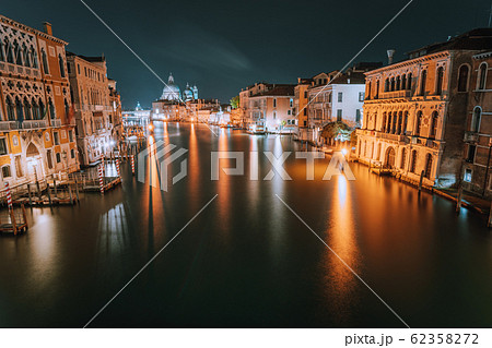 Venice, Italy. Night scene at Grand Canal with reflected light at water surface. Majestic Basilica di Santa Maria della Salute in background Venice, Italy. Night scene at Grand Canal with reflected light at water surface. Majestic Basilica di Santa Maria della Salute in background 62358272