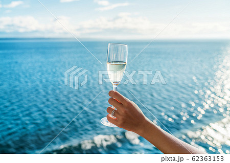 Champagne glass woman's hand toasting on ocean background at luxury cruise ship during sunset. Travel vacation for honeymoon, lady holding flute wearing wedding ring. Champagne glass woman's hand toasting on ocean background at luxury cruise ship during sunset. Travel vacation for honeymoon, lady holding flute wearing wedding ring. 62363153