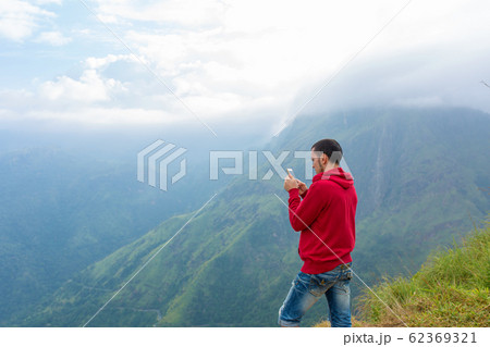 A man enjoying the mountain scenery on the edge of A man enjoying the mountain scenery on the edge of 62369321