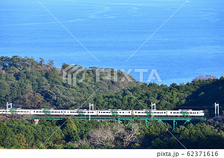 相模湾を見下ろす伊豆急行の鉄橋を渡る特急踊り子号 62371616