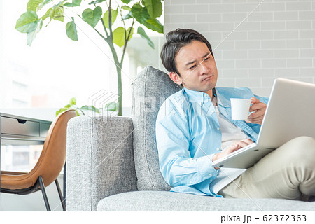自宅のリビングでノートパソコンで仕事をする若い実業家 自宅のリビングでノートパソコンで仕事をする若い実業家 62372363