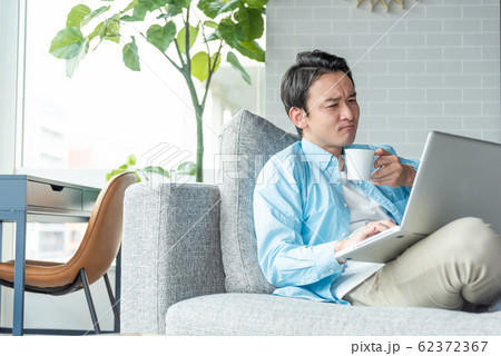 自宅のリビングでノートパソコンで仕事をする若い実業家 自宅のリビングでノートパソコンで仕事をする若い実業家 62372367