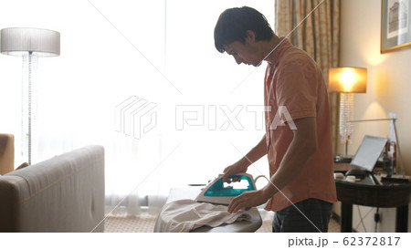 Portrait of young handsome man ironing clothes 62372817