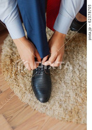 Young businessman ties shoes on a carpet. 62378705