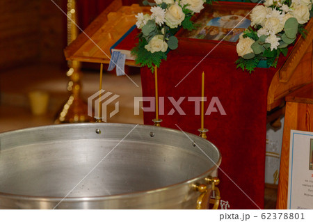 Silver baptismal font with burning candles in a Silver baptismal font with burning candles in a 62378801