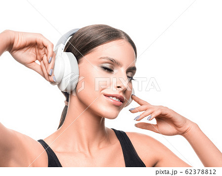Smiling woman with closed eyes listening to the music via headphones. Smiling woman with closed eyes listening to the music via headphones. 62378812