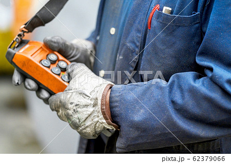 Male hand push remote control switch for overhead crane in the factory, close-up. Electrical control Male hand push remote control switch for overhead crane in the factory, close-up. Electrical control 62379066