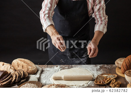 Man sprinkling some flour on dough. Hands kneading dough, cropped view 62382782