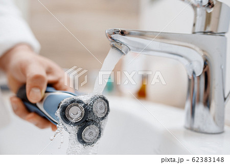 Man cleans electric razor after shaving Man cleans electric razor after shaving 62383148