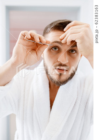 Man removes eyebrow hair, morning hygiene Man removes eyebrow hair, morning hygiene 62383163