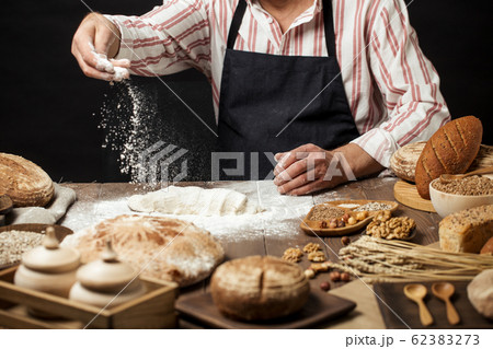 Man sprinkling some flour on dough. Hands kneading dough, cropped view 62383273