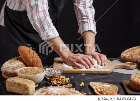 Close up of baker hands kneading dough and making bread with a rolling pin. 62383275
