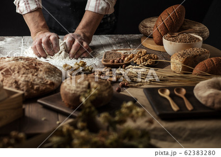 Close up of baker hands kneading dough and making bread with a rolling pin. 62383280