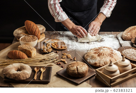 Close up of baker hands kneading dough and making bread with a rolling pin. 62383321