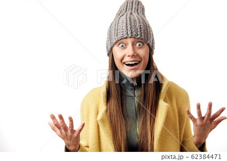 Beautiful bug eyed woman expresses happy emotions, has broad pleasant smile, dressed in warm topcoat and fashionable hat 62384471