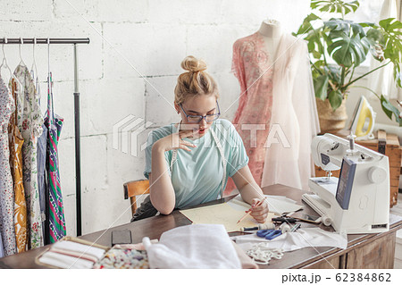 Fashion designer at work. Talanted dressmaker drawing sketch at her workspace Fashion designer at work. Talanted dressmaker drawing sketch at her workspace 62384862