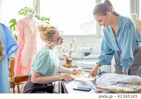 Female seamstress discussing features of the order with client in cozy studio 62385165