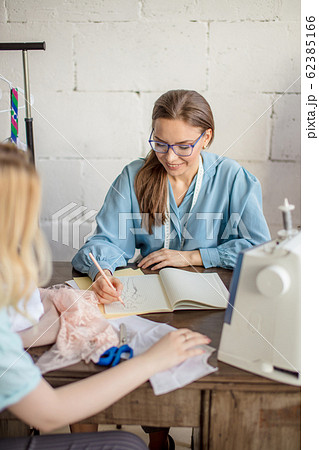 Female seamstress discussing features of the order with client in cozy studio 62385166