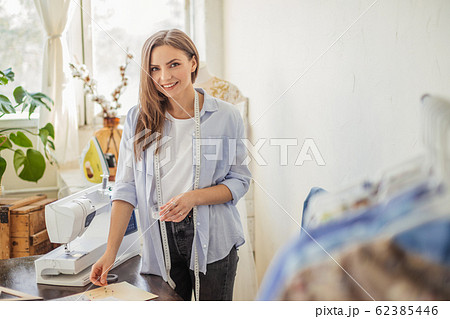 Beautiful seamstress is working with a wedding dress model in her studio 62385446