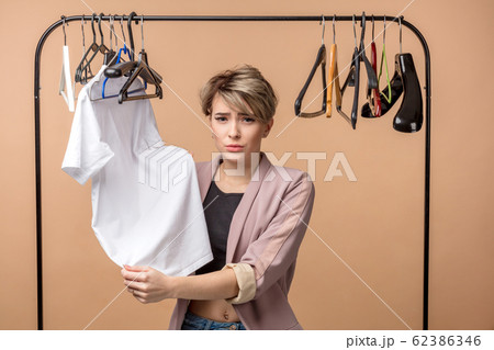 beautiful customer is holding a T-shirt and looking at the camera 62386346