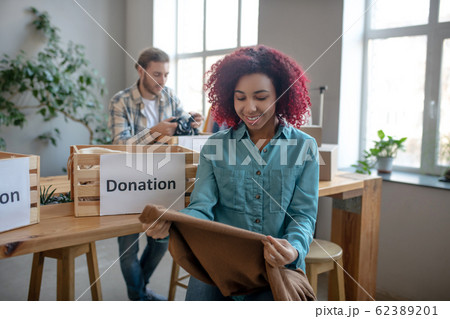 Joyful young girl with brown pullover in her hands. 62389201