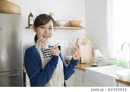 キッチンでスマホをチェックする若い主婦 62393933