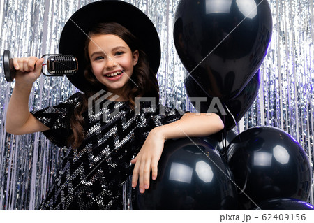 attractive european young girl singing with a microphone at a party against a background of black 62409156
