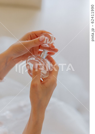 Beautiful young bride holds perfume in her hands. 62411990