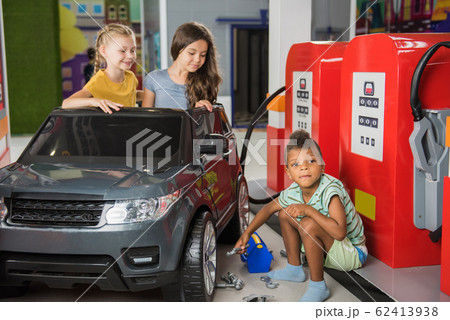 Little auto mechanic repairing toy car in playroom. 62413938