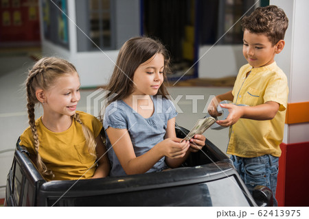 Little girls sitting in toy car at entertainment center. Little girls sitting in toy car at entertainment center. 62413975