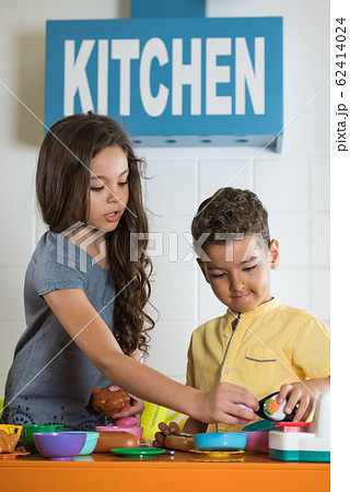 Little girl and boy playing with toy kitchen. Little girl and boy playing with toy kitchen. 62414024