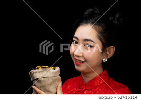 Portrait Asian young woman red dress traditional cheongsam holding a gold coin in a sack at the black background 62416114